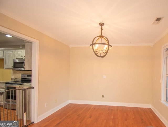 unfurnished dining area featuring hardwood / wood-style floors, crown molding, and a chandelier