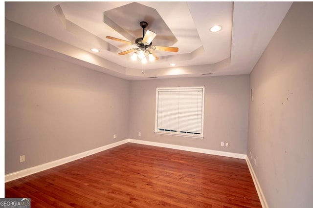 spare room featuring ceiling fan, wood-type flooring, and a tray ceiling