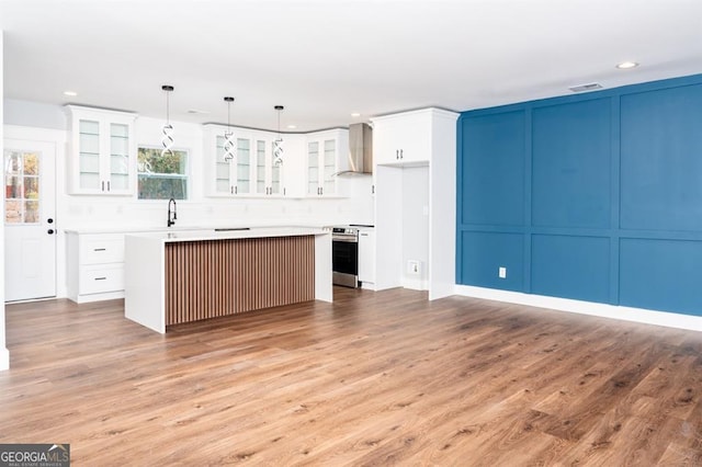 kitchen with a kitchen island, wood-type flooring, decorative light fixtures, electric stove, and white cabinets