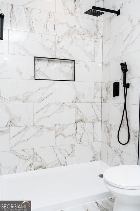 bathroom with tiled shower and toilet