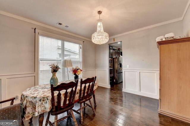 dining room with dark hardwood / wood-style flooring, an inviting chandelier, and ornamental molding