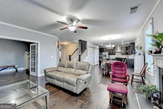 living room with a wealth of natural light, crown molding, dark wood-type flooring, and ceiling fan with notable chandelier