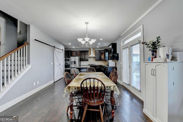 dining space featuring dark hardwood / wood-style flooring, a barn door, and a notable chandelier