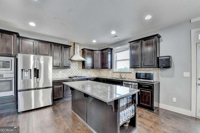 kitchen featuring dark hardwood / wood-style flooring, stainless steel appliances, a kitchen island, and wall chimney exhaust hood