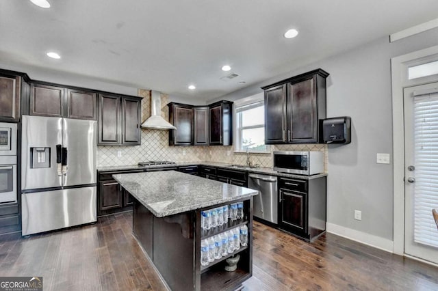 kitchen featuring wall chimney exhaust hood, a center island, stainless steel appliances, and dark wood-type flooring