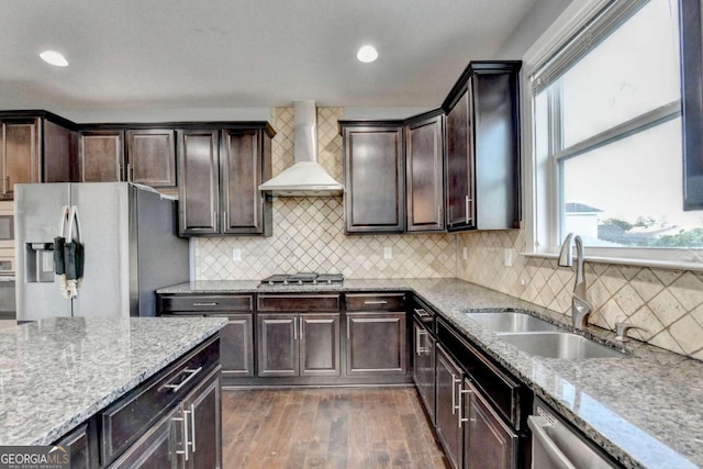 kitchen with decorative backsplash, stainless steel appliances, sink, wall chimney range hood, and dark hardwood / wood-style floors