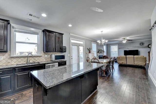 kitchen featuring sink, dark wood-type flooring, a kitchen bar, a kitchen island, and ornamental molding