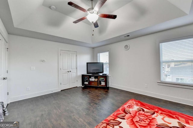 living room with dark hardwood / wood-style flooring, a raised ceiling, and ceiling fan