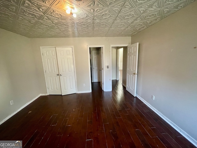 unfurnished bedroom with dark hardwood / wood-style floors and a closet