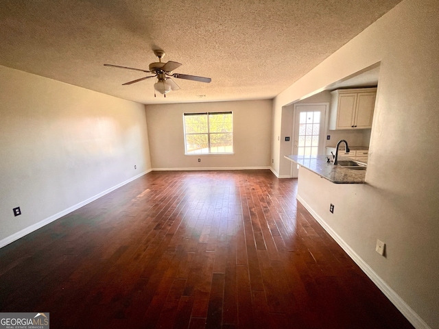 unfurnished living room featuring a textured ceiling, ceiling fan, dark hardwood / wood-style flooring, and sink