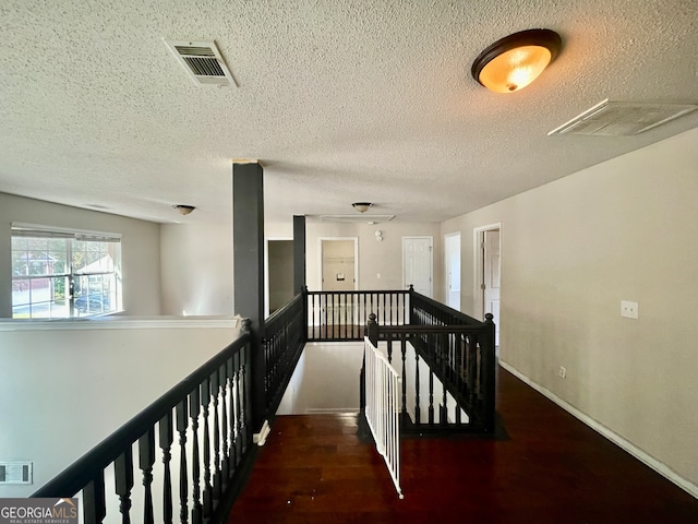 corridor featuring a textured ceiling and dark wood-type flooring