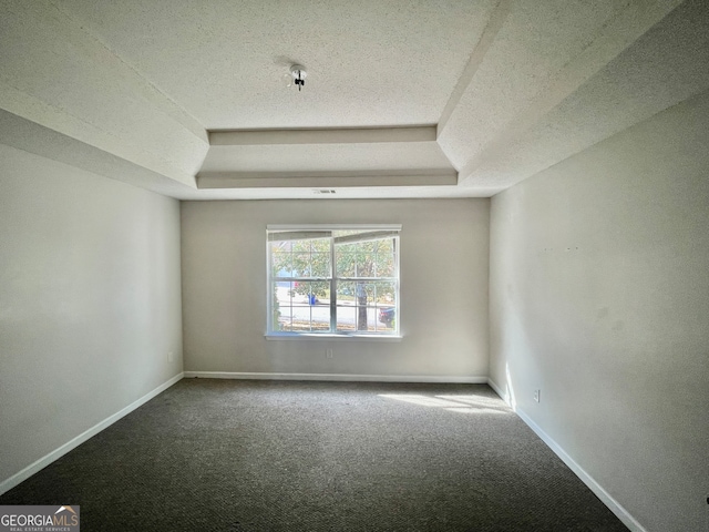 empty room with carpet flooring, a textured ceiling, and a tray ceiling