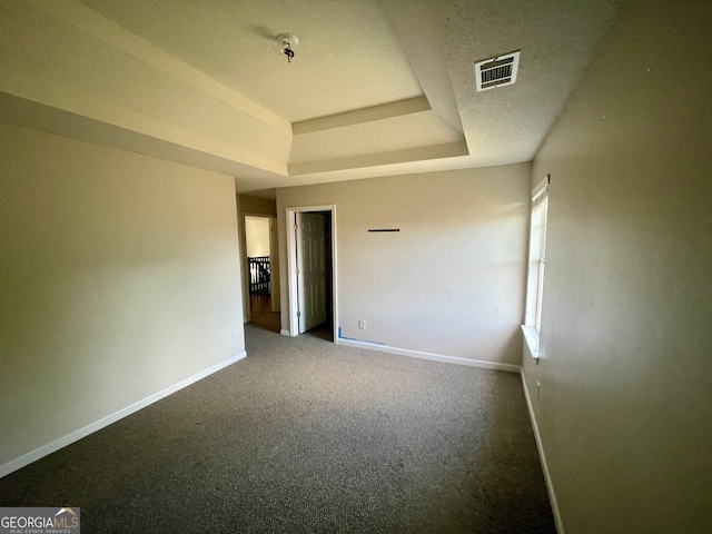 carpeted empty room with a textured ceiling and a tray ceiling