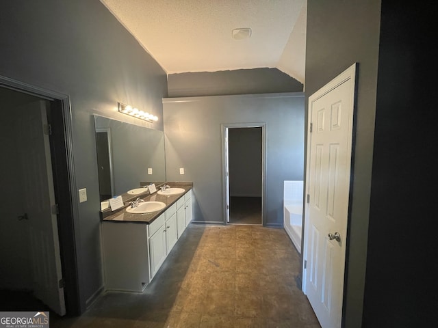 bathroom featuring a washtub, vanity, and vaulted ceiling