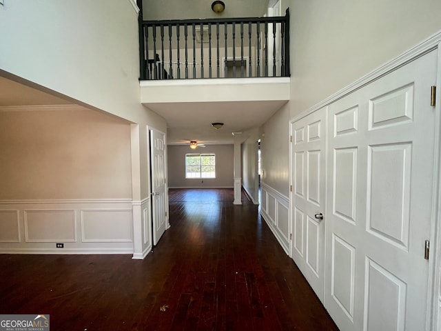 hallway featuring dark hardwood / wood-style flooring, ornamental molding, and a high ceiling