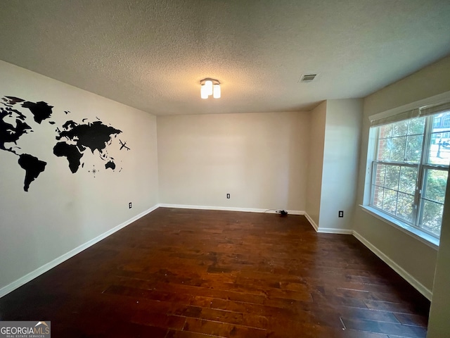 empty room with dark hardwood / wood-style flooring and a textured ceiling