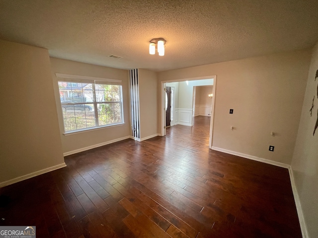 spare room with dark hardwood / wood-style floors and a textured ceiling