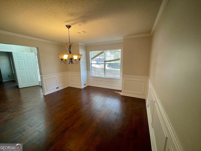 unfurnished dining area with a textured ceiling, dark hardwood / wood-style flooring, an inviting chandelier, and ornamental molding