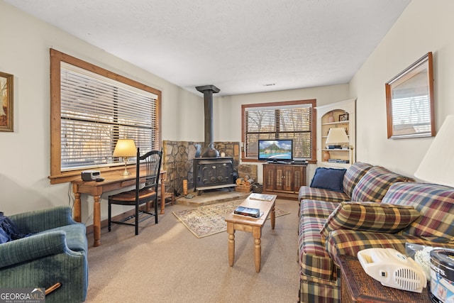 living room featuring light carpet, a textured ceiling, and a wood stove