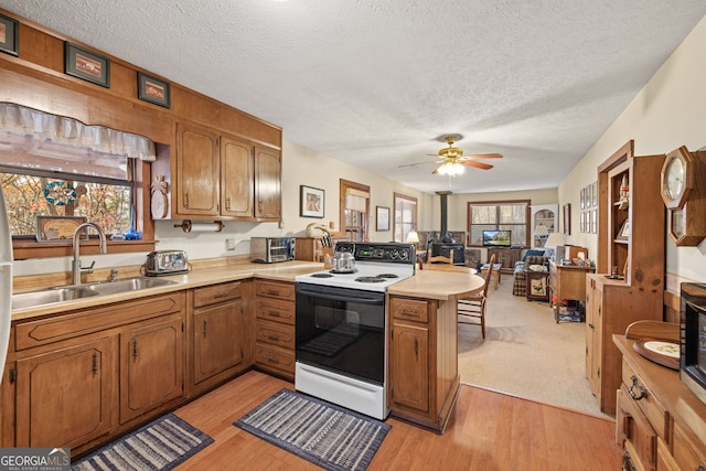 kitchen featuring sink, kitchen peninsula, a textured ceiling, electric stove, and light wood-type flooring