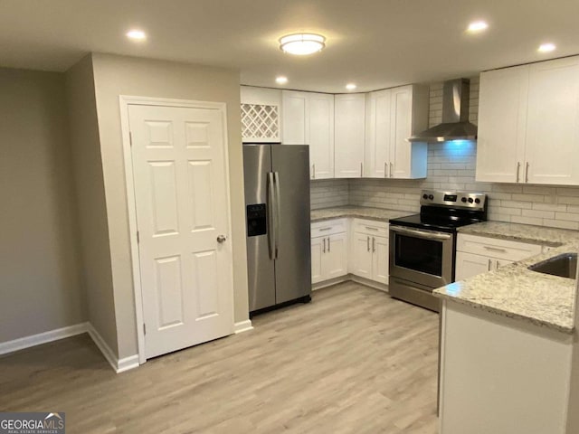 kitchen with white cabinets, appliances with stainless steel finishes, light hardwood / wood-style flooring, and wall chimney exhaust hood