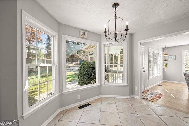 unfurnished dining area with light tile patterned floors, a textured ceiling, and a healthy amount of sunlight