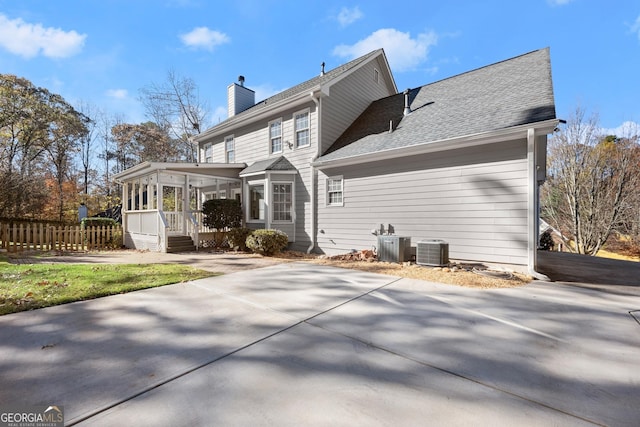 rear view of house featuring central AC unit and a sunroom