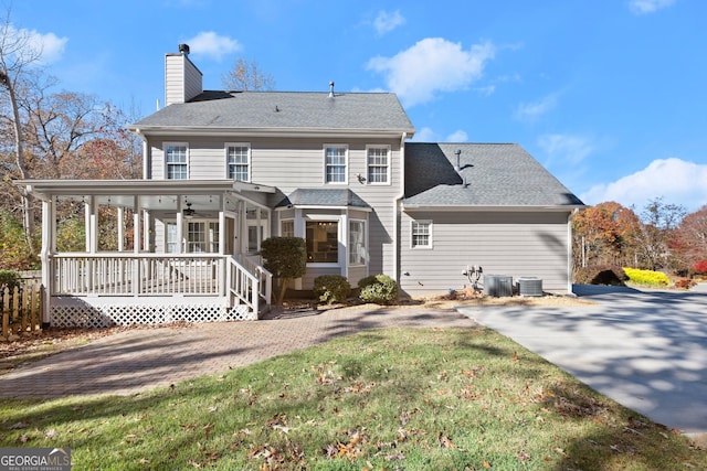 back of property with a lawn, ceiling fan, covered porch, and central air condition unit