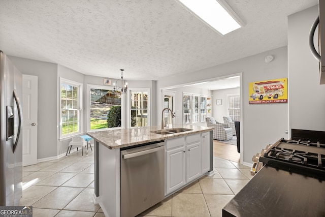 kitchen featuring sink, hanging light fixtures, stainless steel appliances, a kitchen island with sink, and light tile patterned floors