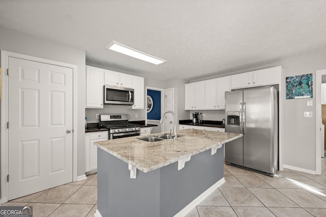 kitchen with a textured ceiling, sink, stainless steel appliances, and a kitchen island with sink