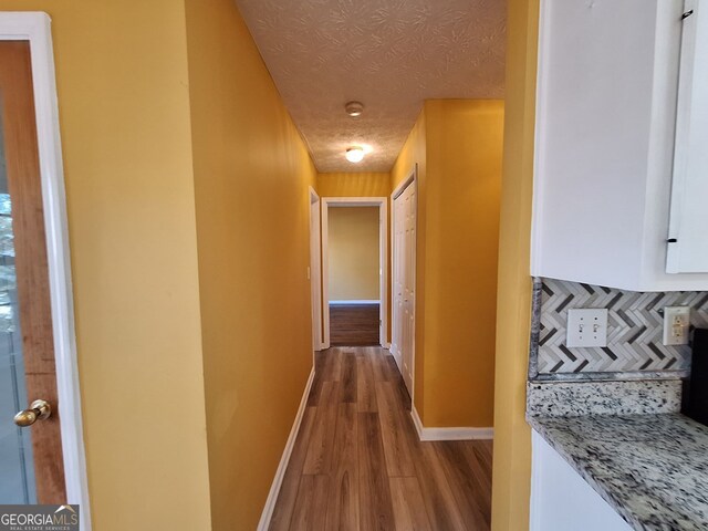 unfurnished bedroom featuring a textured ceiling, built in desk, and dark hardwood / wood-style floors