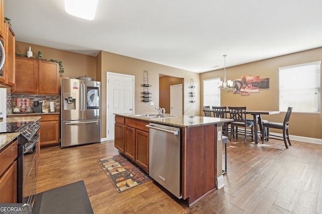 kitchen with a healthy amount of sunlight, an island with sink, pendant lighting, and appliances with stainless steel finishes