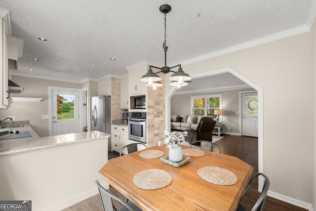 dining room featuring a textured ceiling, crown molding, dark hardwood / wood-style floors, and a notable chandelier