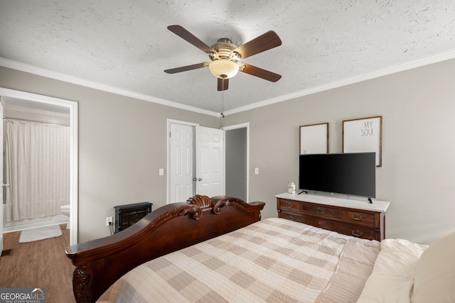 bedroom featuring ornamental molding, a textured ceiling, ceiling fan, hardwood / wood-style floors, and connected bathroom