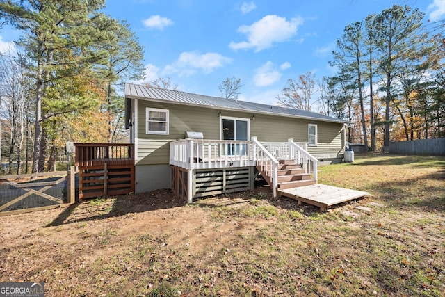 rear view of property featuring a lawn and a deck