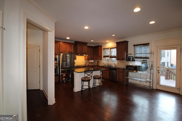 kitchen featuring a breakfast bar area, tasteful backsplash, dark hardwood / wood-style flooring, a kitchen island, and stainless steel appliances