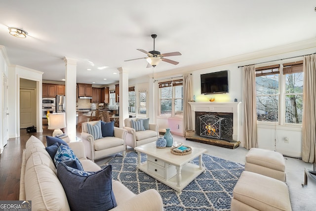 living room featuring a high end fireplace, ornamental molding, ceiling fan, and ornate columns