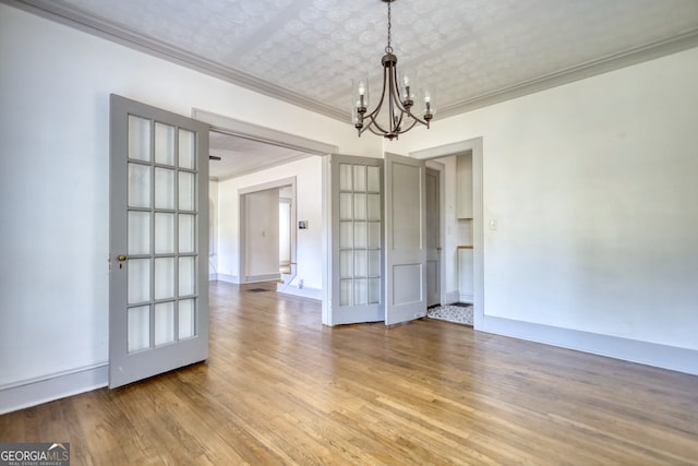 unfurnished dining area featuring crown molding, light hardwood / wood-style flooring, french doors, and a notable chandelier