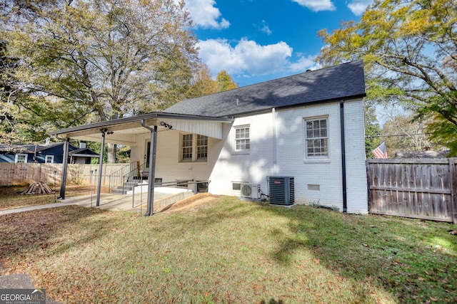 back of property with ac unit, a yard, and central AC unit