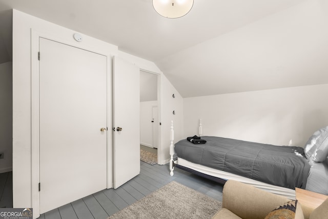 bedroom with wood-type flooring and vaulted ceiling