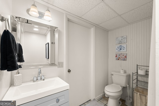 bathroom with tile patterned floors, a drop ceiling, vanity, and toilet