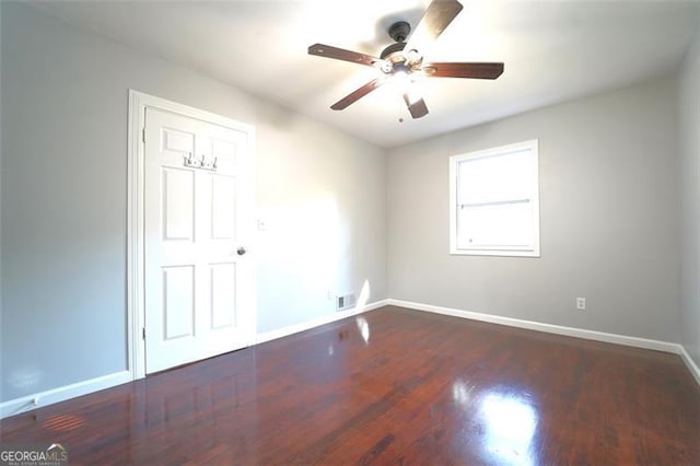 empty room with dark hardwood / wood-style floors and ceiling fan