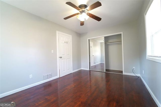 unfurnished bedroom featuring ceiling fan, dark wood-type flooring, and a closet