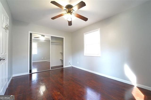 unfurnished bedroom with ceiling fan, a closet, and dark wood-type flooring