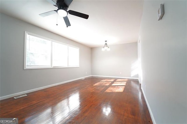 spare room with ceiling fan with notable chandelier and dark hardwood / wood-style flooring