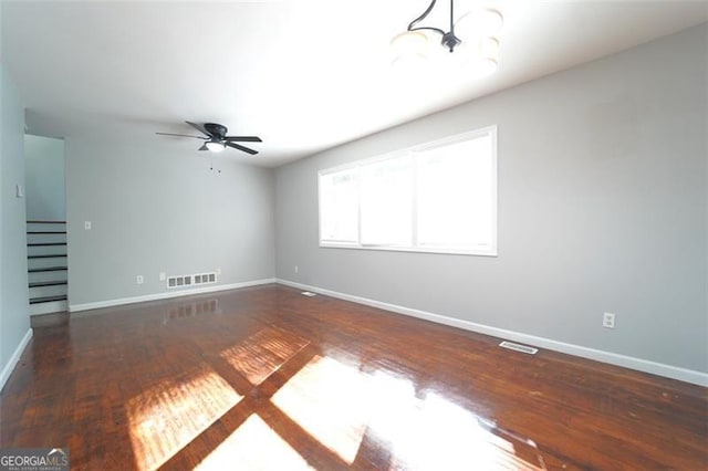 interior space featuring dark wood-type flooring and ceiling fan with notable chandelier