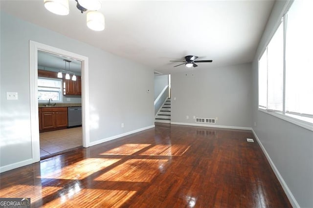 unfurnished living room featuring hardwood / wood-style floors, ceiling fan with notable chandelier, and sink