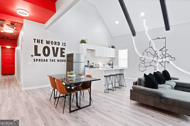 dining area with beamed ceiling, high vaulted ceiling, and light wood-type flooring