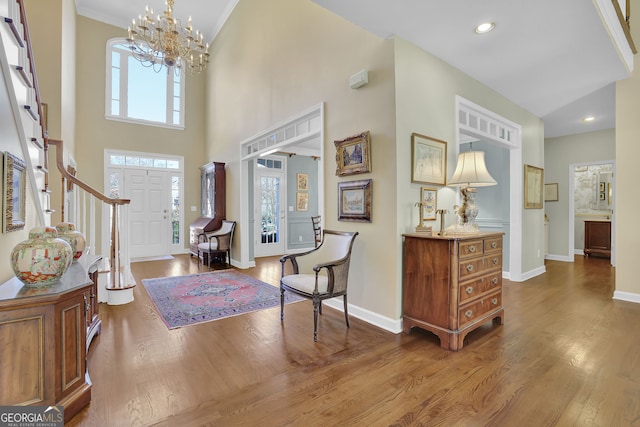 entrance foyer with a chandelier, a high ceiling, dark hardwood / wood-style flooring, and crown molding