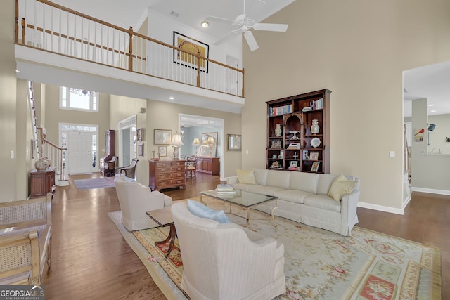 living room featuring ceiling fan, a towering ceiling, and wood-type flooring